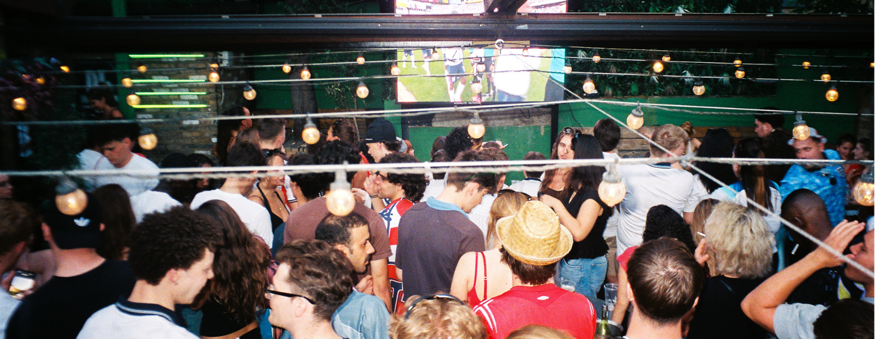 Photograph of a football crowd watching TV in the Abbey Tavern beer garden